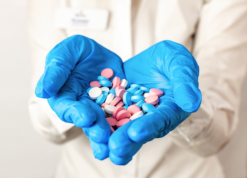 A healthcare professional holding a handful of medication