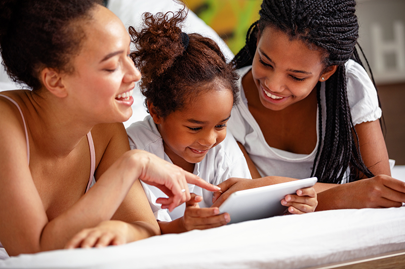 Three African American girls looking at a tablet screen